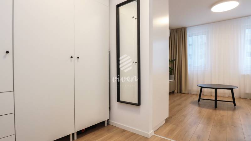 Nábytek v 1-pokojovém bytě s podlahou s dřevěným dekorem a černým stolkem.