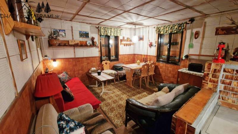 Rustikální interiér chaty s pohovkami, dřevěným dekorem a dekoracemi v útulné atmosféře.