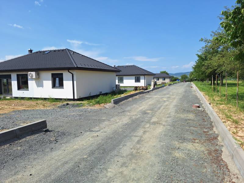 Rodinné domy na ulici Vyšná Šebastová v Prešově obklopené zelení, vedle nedokončené cesty.