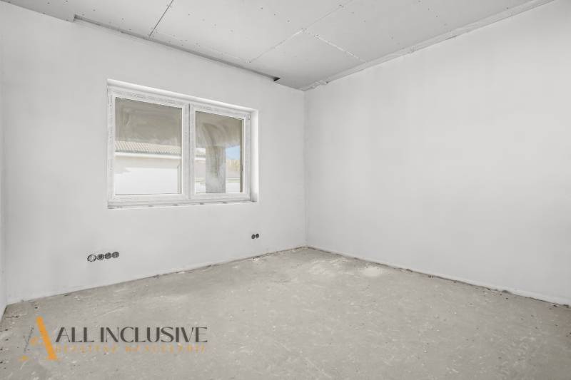 Stavební místnost v rodinném domě s oknem a neupravenou podlahou, připravená k dokončení.