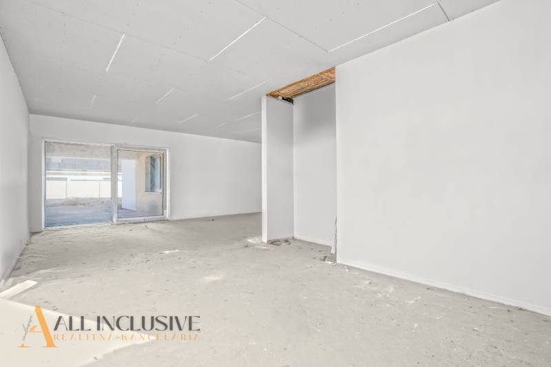 Prostorná místnost v rodinném domě s nedokončenou podlahou a velkým oknem.