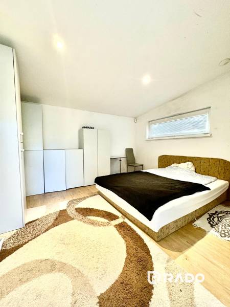 Ložnice v rodinném domě s postelí, skříňkami a podlahou s dřevěným dekorem.