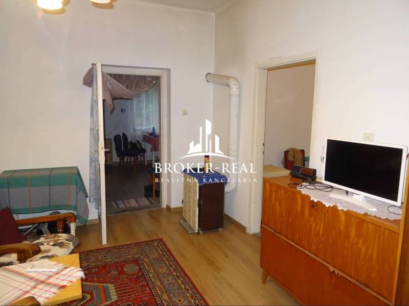 Obývací pokoj v rodinném domě s kobercem a podlahou s dřevěným dekorem.