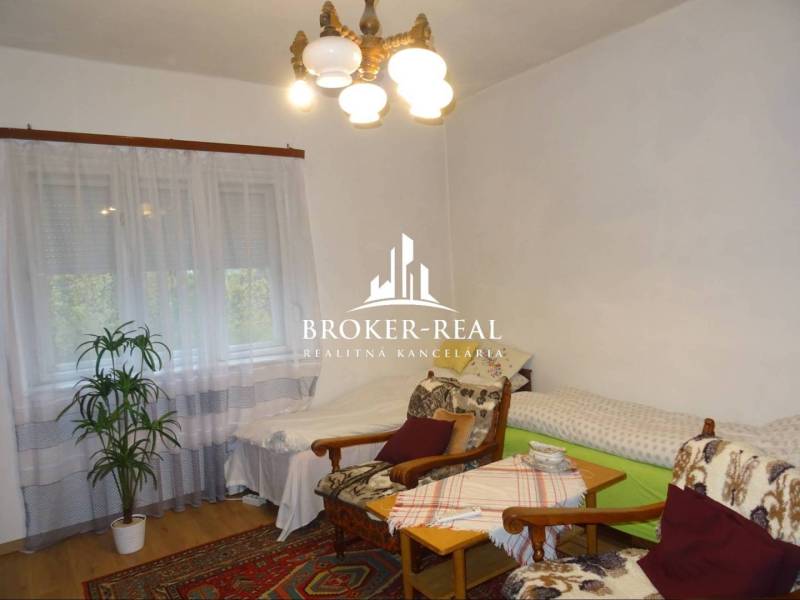 Pohodlný pokoj v rodinném domě s křesly, postelemi a podlahou s dřevěným dekorem.