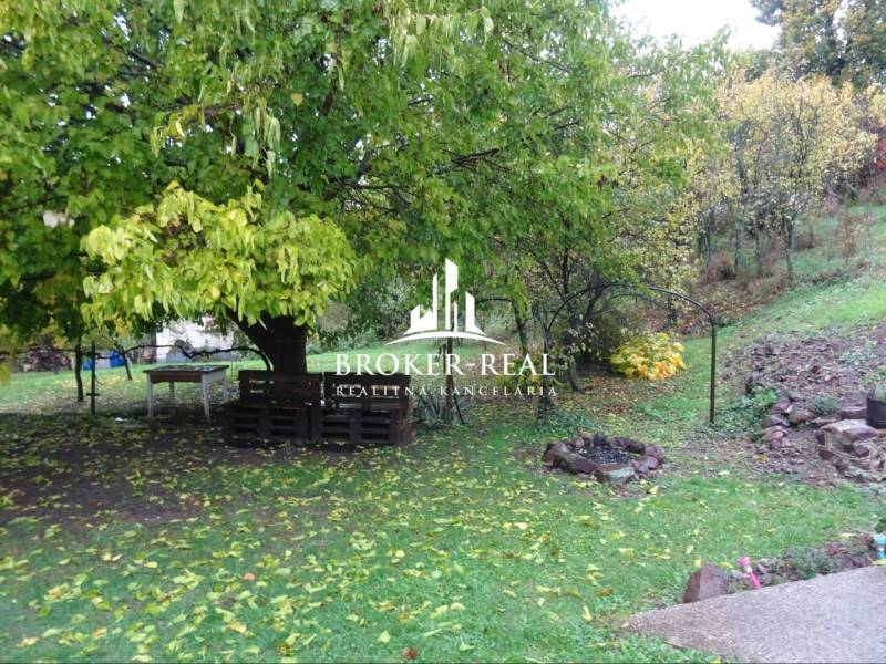 Zahrada u rodinného domu ve Fony, s posezením z palet a ohništěm.