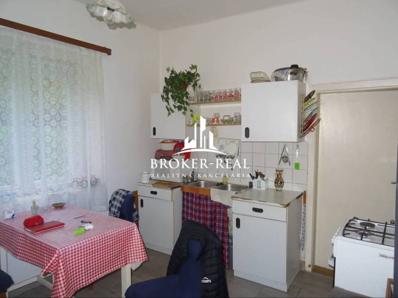 Kuchyně v rodinném domě s klasickým zařízením, záclony, bílý kuchyňský nábytek.