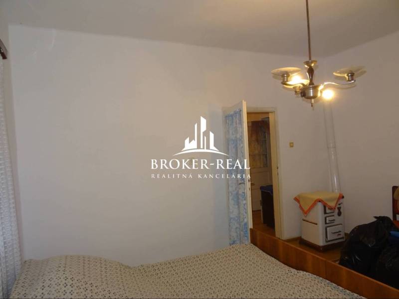 Ložnice v rodinném domě s jednoduchým zařízením a retro vytápěním.