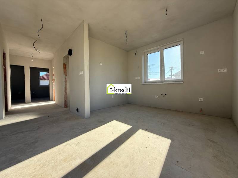 Interiér rodinného domu s nedokončenými stěnami a oknem, podlaha s dřevěným dekorem.