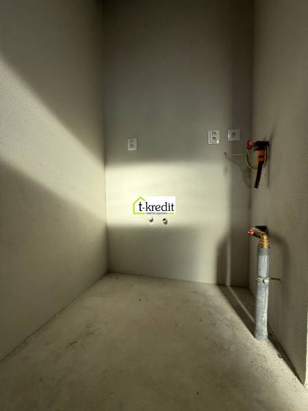 Prázdná místnost s betonovou podlahou a instalacemi v rodinném domě.