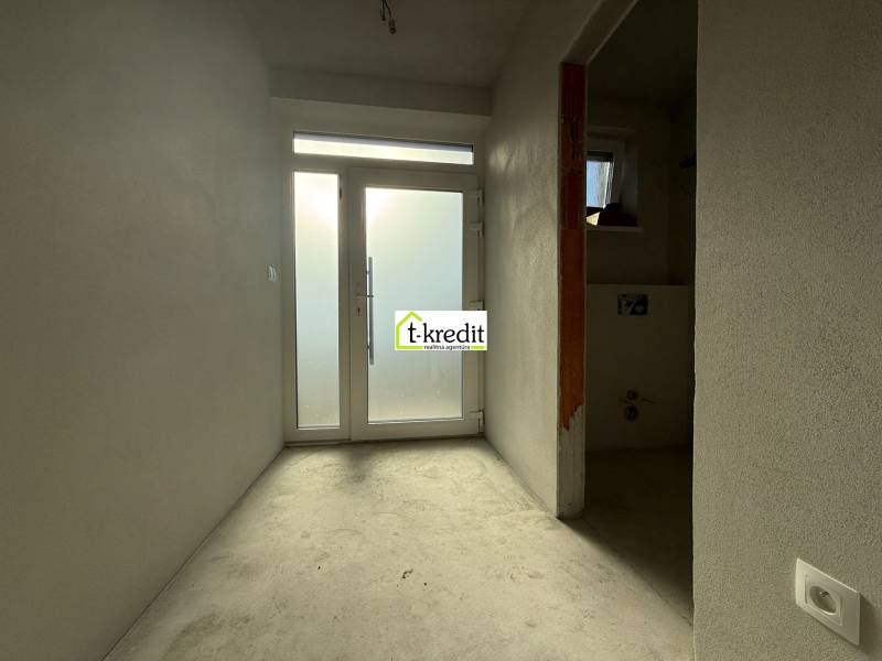 Interiér rodinného domu s bílými stěnami a prosklenými dveřmi na konci chodby.