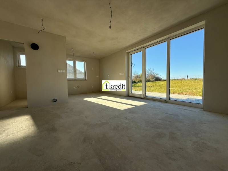 Prostorný interiér rodinného domu s velkými okny a výhledem na zahradu.