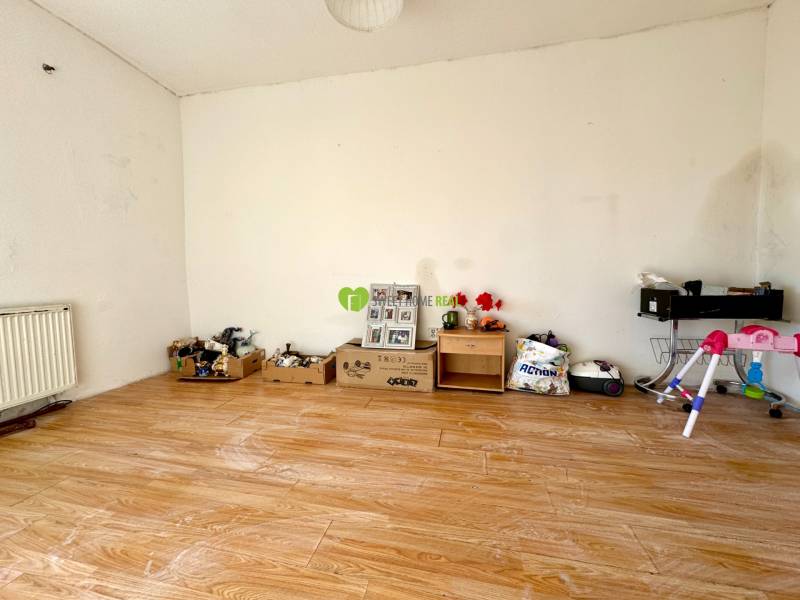 Pokoj v rodinném domě s podlahou s dřevěným dekorem a různými předměty u stěny.