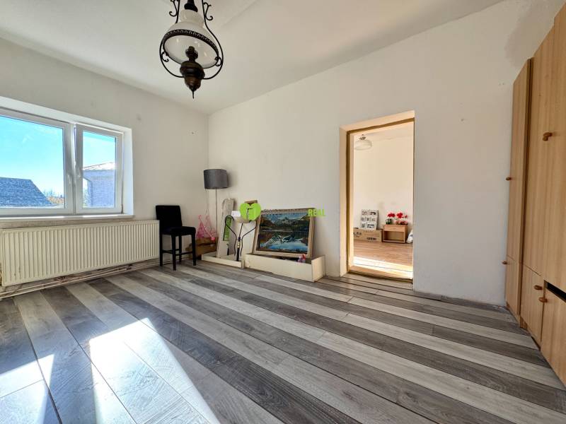 Pokoj v rodinném domě s lampou, obrazem a podlahou s dřevěným dekorem.