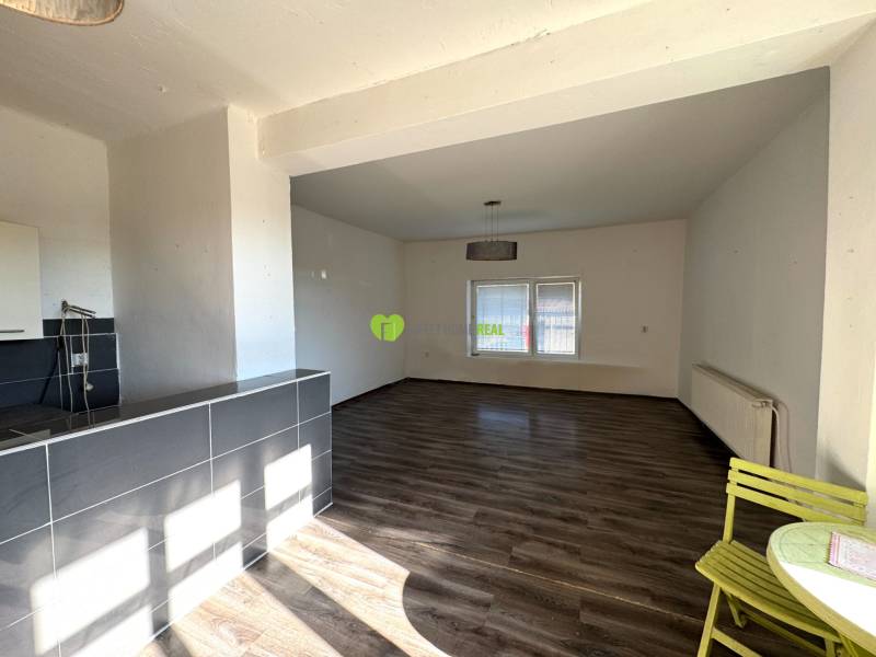 Interiér rodinného domu s prostornou místností, podlaha s dřevěným dekorem a jídelní kout.