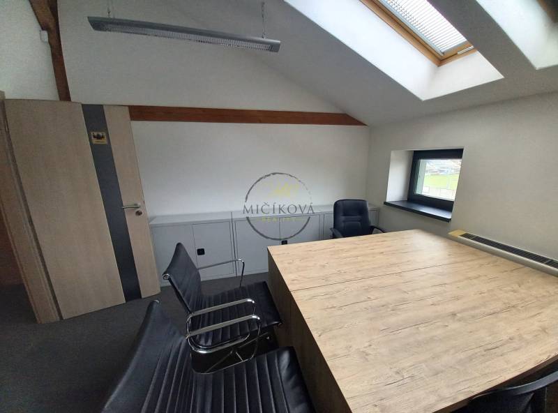 Interiér kanceláře s konferenčním stolem a křesly, podlaha s dřevěným dekorem.