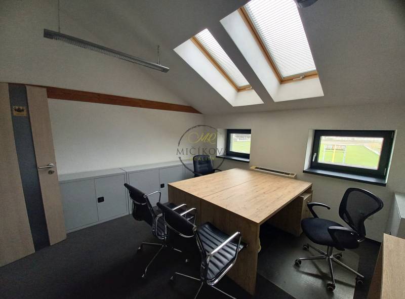 Kancelář s pracovním stolem a židlemi, pod střešními okny, s podlahou s dřevěným dekorem.