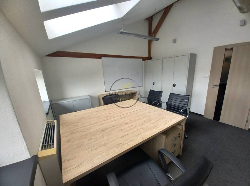 Kancelář s podlahou s dřevěným dekorem, střešním oknem a černými židlemi.