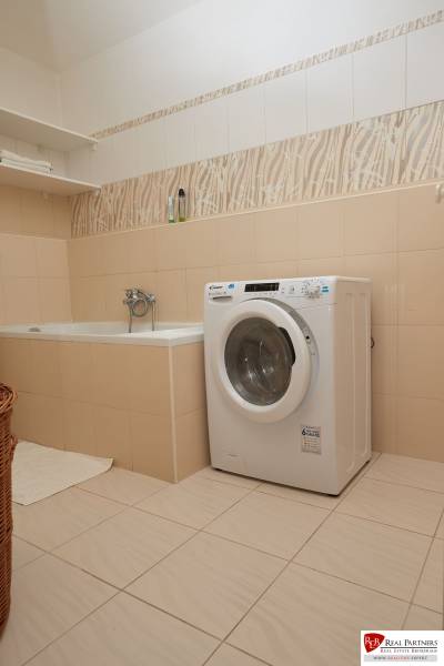 Koupelna s vanou, pračkou a policí v 2-pokojovém bytě.