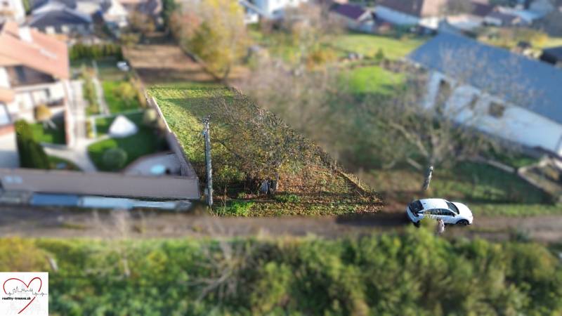 Pozemky - bydlení na ulici M.H. Chvotekové v Dolní Krupé, se zelení a zaparkovaným autem.