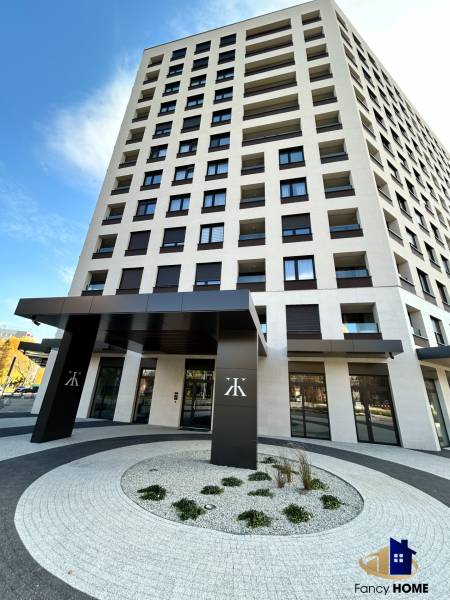 Výšková budova na Karpatské ulici v Popradu s moderním vstupem a oblými chodníky.