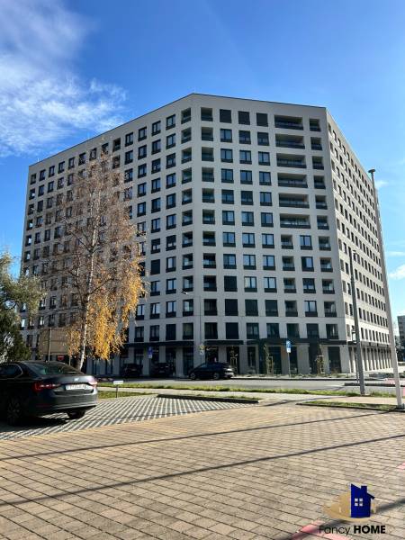 Bytový dům na Karpatské ulici v Popradu, okolní parkoviště a stromy.