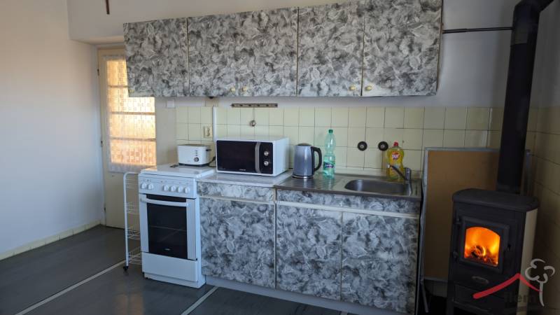 Kuchyně s obkladem, sporákem a krbem v rodinném domě, podlaha s dřevěným dekorem.