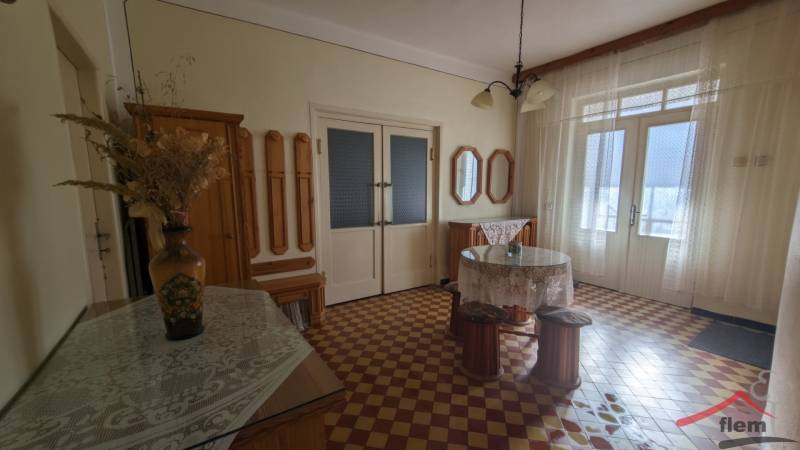 Interiér rodinného domu s barevnou dlažbou, květinovou vázou a záclonami.