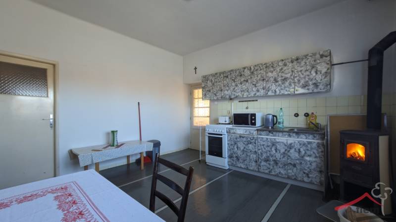 Kuchyně v rodinném domě s kamny a kuchyňskou linkou, podlaha s dřevěným dekorem.