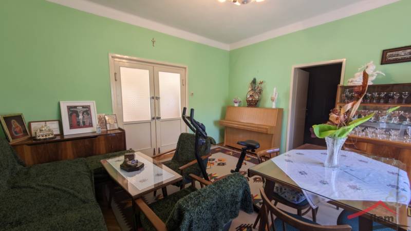 Obývací pokoj v rodinném domě s nábytkem, cvičebním zařízením a zelenými stěnami.