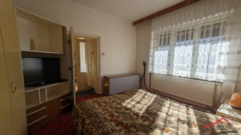 Ložnice v rodinném domě s televizorem a květinovým vzorem ložního prádla.