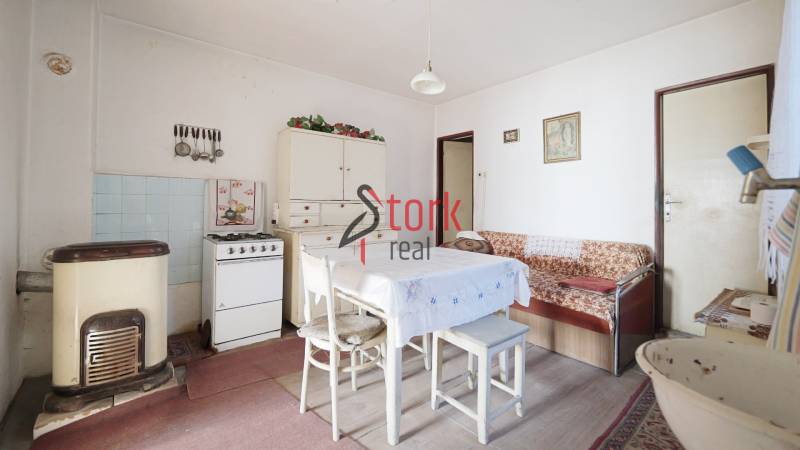 Jídelna s plynovým sporákem, stolem a pohovkou v rodinném domě, podlaha s dřevěným dekorem.