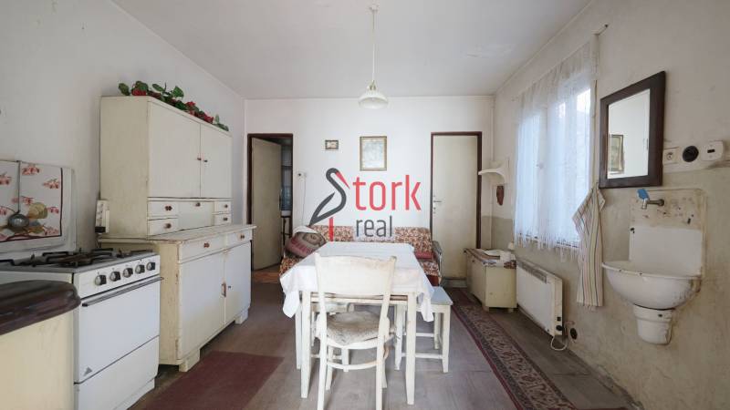 Kuchyně v rodinném domě s retro nábytkem, stolem a umyvadlem, podlaha s dřevěným dekorem.