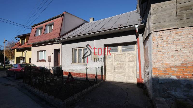 Rodinný dům na Kostelní ulici v Rajci s autem vpředu a dřevěným plotem.