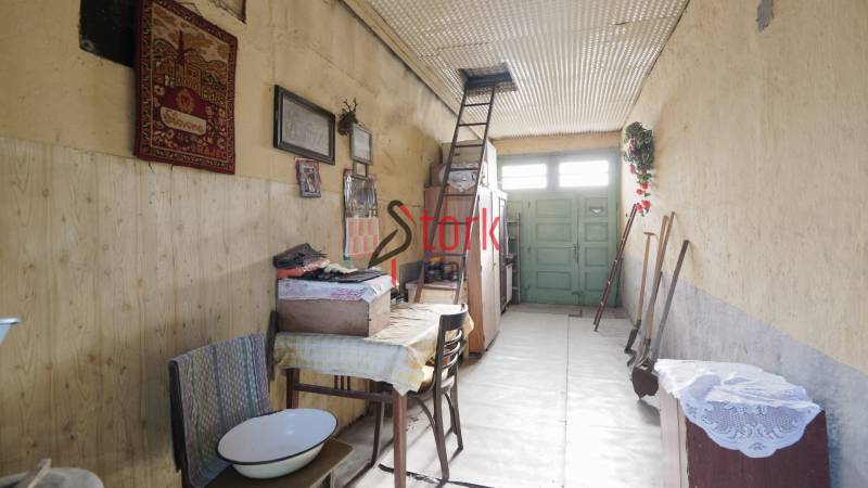 Interiér rodinného domu s žebříkem vedle vyšívané tapisérie. Podlaha s dřevěným dekorem.