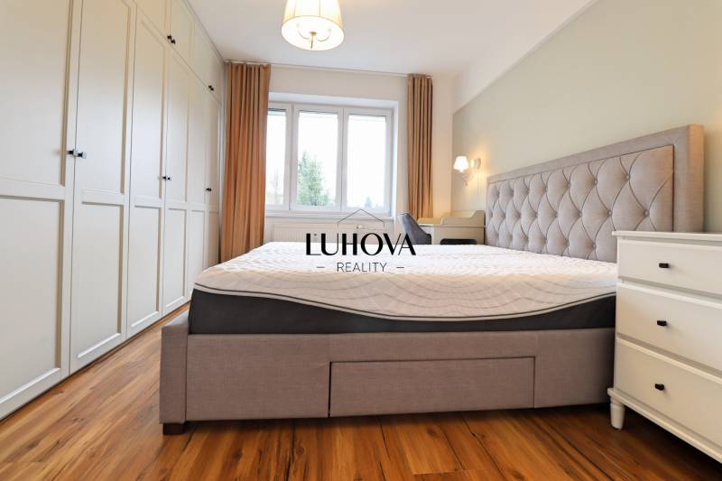 Světlá ložnice s velkou postelí, vestavěnou skříní a podlahou s dřevěným dekorem v 3-pokojovém bytě.