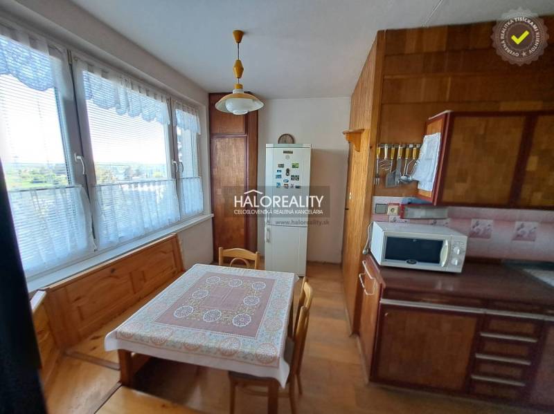 Obývací pokoj v 3-pokojovém bytě s podlahou s dřevěným dekorem, sedací souprava a nástěnné dekorace.