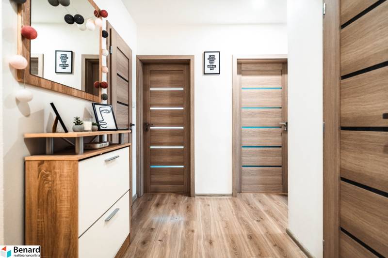 Interiér 2-pokojového bytu s podlahou s dřevěným dekorem, dveřmi a dekoracemi.