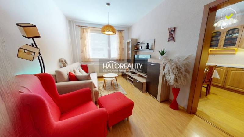 Obývací pokoj v 2pokojovém bytě s podlahou s dřevěným dekorem a červenými křesly.