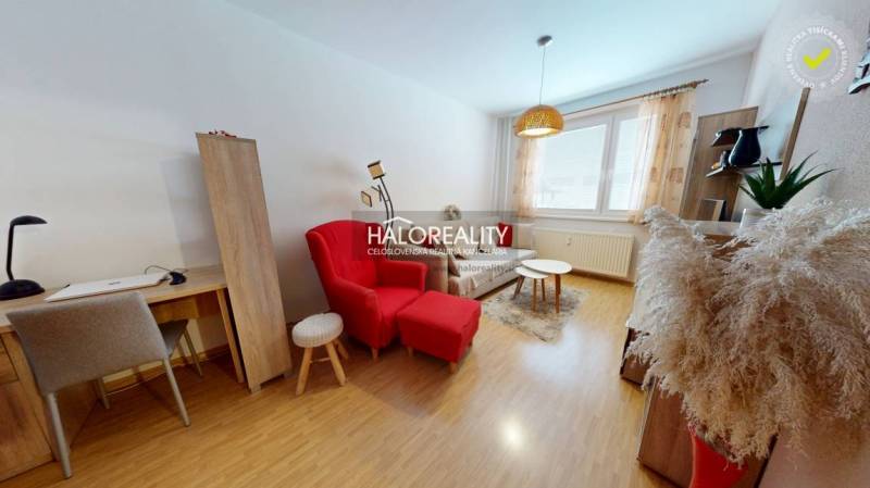 Obývací pokoj v 2-pokojovém bytě se stolkem, červeným křeslem a podlahou s dřevěným dekorem.