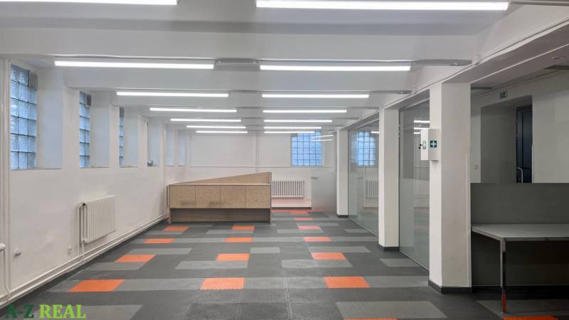 Obchodní prostory s barevnou podlahou a prosklenými příčkami, vhodné pro kanceláře nebo provozovnu.