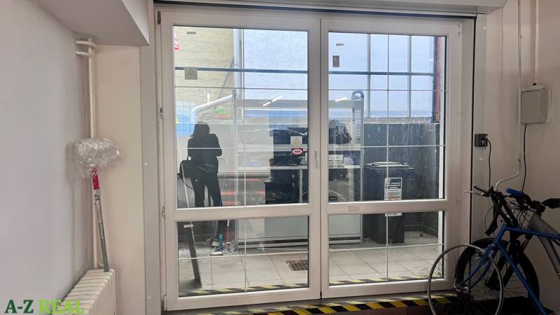 Skleněné posuvné dveře v obchodních prostorách, kolo, radiátor a plastová fólie na stěně.