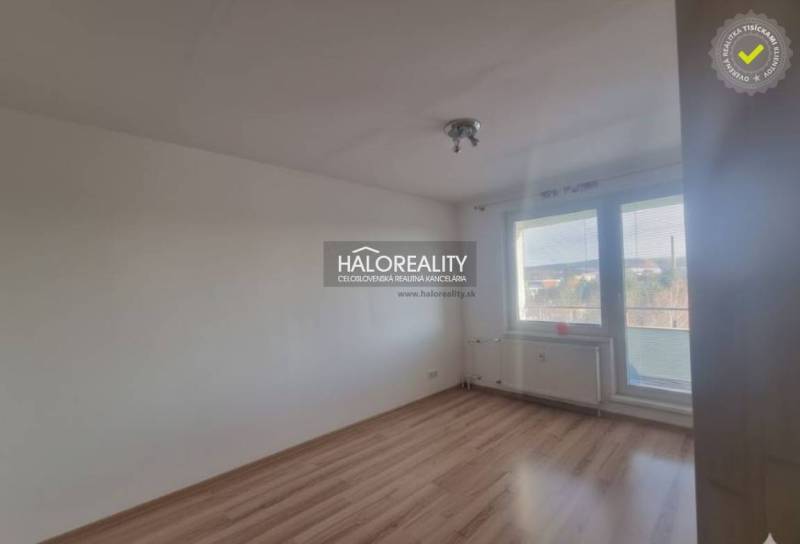 Pokoj s podlahou s dřevěným dekorem a velkým oknem ve 3pokojovém bytě.