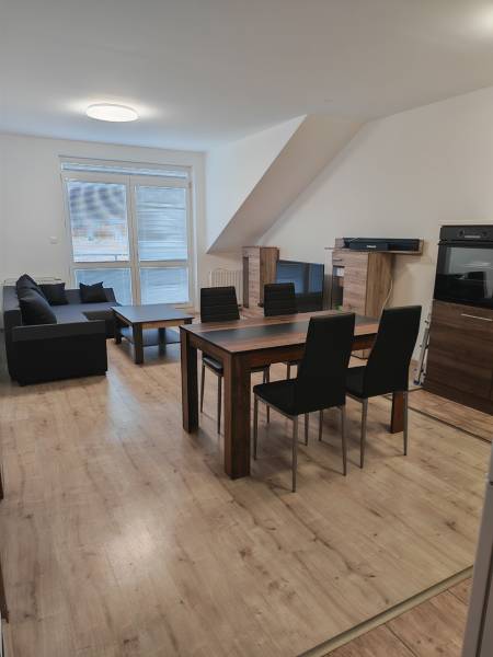 Obývací pokoj ve 3-pokojovém bytě s podlahou s dřevěným dekorem a jídelním stolem.