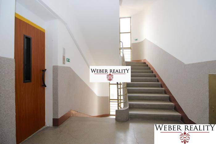 Chodba s výtahem a schodištěm, vedoucí do patra v 2-pokojovém bytě.