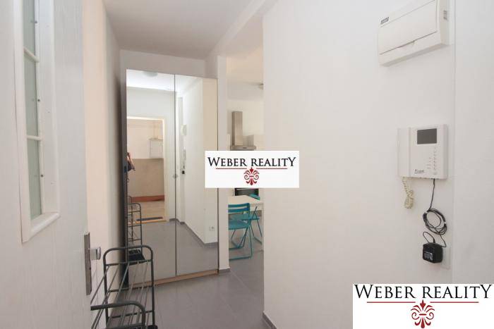 Chodba v 2-pokojovém bytě s věšákem, zrcadlem a dlažbou.