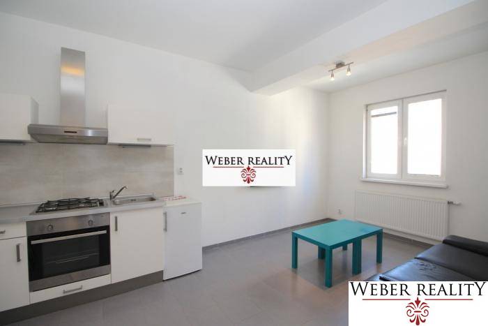 Kuchyně v 2-pokojovém bytě s šedou podlahou, kuchyňskou linkou a posezením.