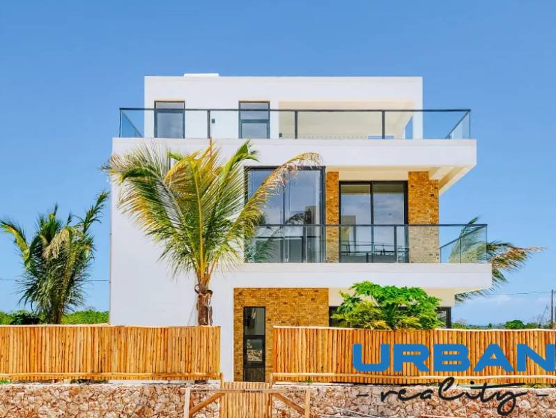 Vila ve Fumba Town se skleněnými balkóny a exotickými palmami v popředí.