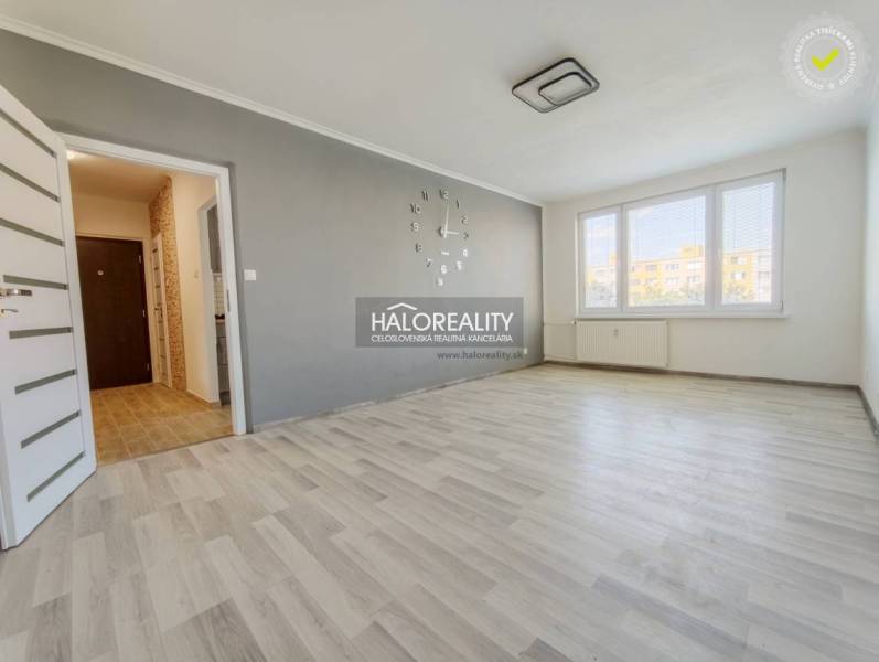 Obývací pokoj v 2pokojovém bytě s podlahou s dřevěným dekorem a velkými okny.