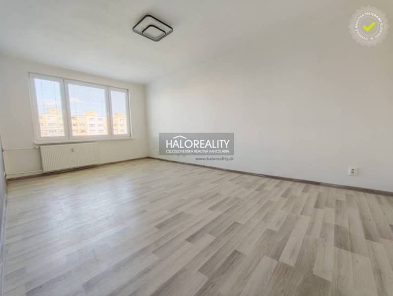 Pokoj s velkými okny a podlahou s dřevěným dekorem ve 2pokojovém bytě.