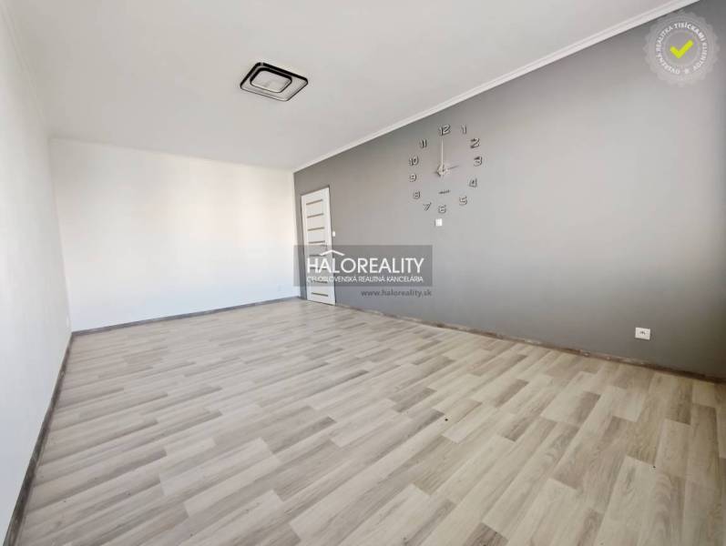 Pokoj s hodinami a podlahou s dřevěným dekorem ve 2-pokojovém bytě.